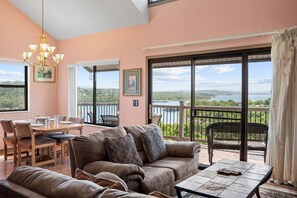 A room with a dining table, sofa, and chairs, a chandelier, and a balcony with a view of the landscape. - Best-View 3-Bedroom Condo, Close to Silver Dollar City with Free Tickets & Outdoor Pool (Branson)