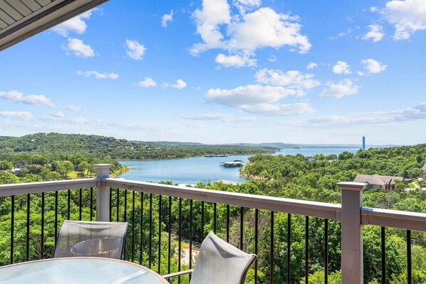 A balcony with a table and chairs overlooking a lake, surrounded by greenery and a clear sky. - Best-View 3-Bedroom Condo, Close to Silver Dollar City with Free Tickets & Outdoor Pool (Branson)
