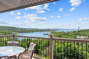 A balcony with a table and chairs, overlooking a lake and forested area. - Best-View 3-Bedroom Condo, Close to Silver Dollar City with Free Tickets & Outdoor Pool (Branson)