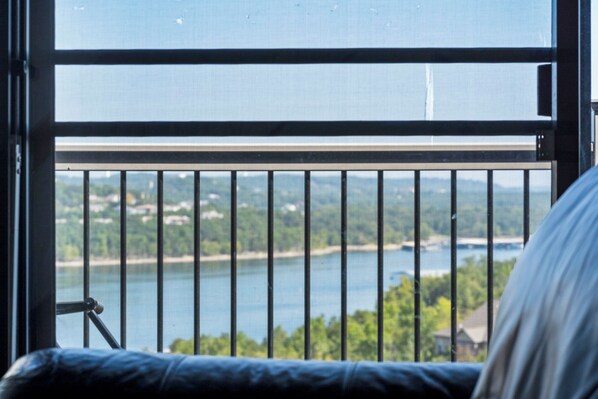 A balcony with a metal railing overlooking a body of water and greenery.