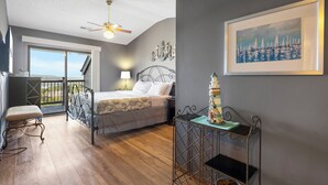 Una camera da letto con un letto, una scrivania, una sedia, un balcone e un quadro.