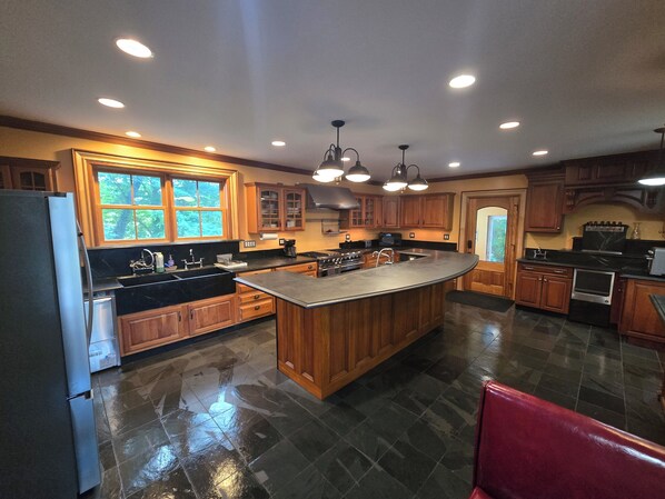 A kitchen with a central island, wooden cabinets, a refrigerator, and a stove. - KATERINA OF OLD SARATOGA (Schuylerville)