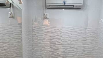 Een bad/douchecombinatie, een haardroger, handdoeken, zeep