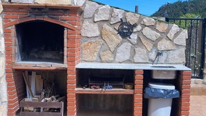 An outdoor brick oven with a stone wall backdrop and a metal grill. - La Caseta Rural House (La Casa De La Noguera)