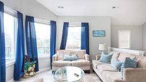 A living room with two beige sofas, a glass coffee table, and a lamp. - Short walk to Beach with Pool, Game Room, and Spa! (Corolla)