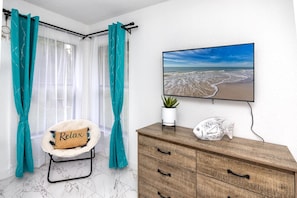 Enjoy a serene beach view from the comfort of your room, featuring a dresser, chair, and potted plant.