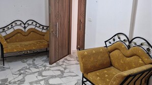 A room with two sofas, a wooden door, and a tiled floor.