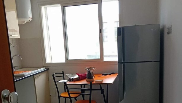 A compact kitchen with a refrigerator, a sink, and a window providing natural light.