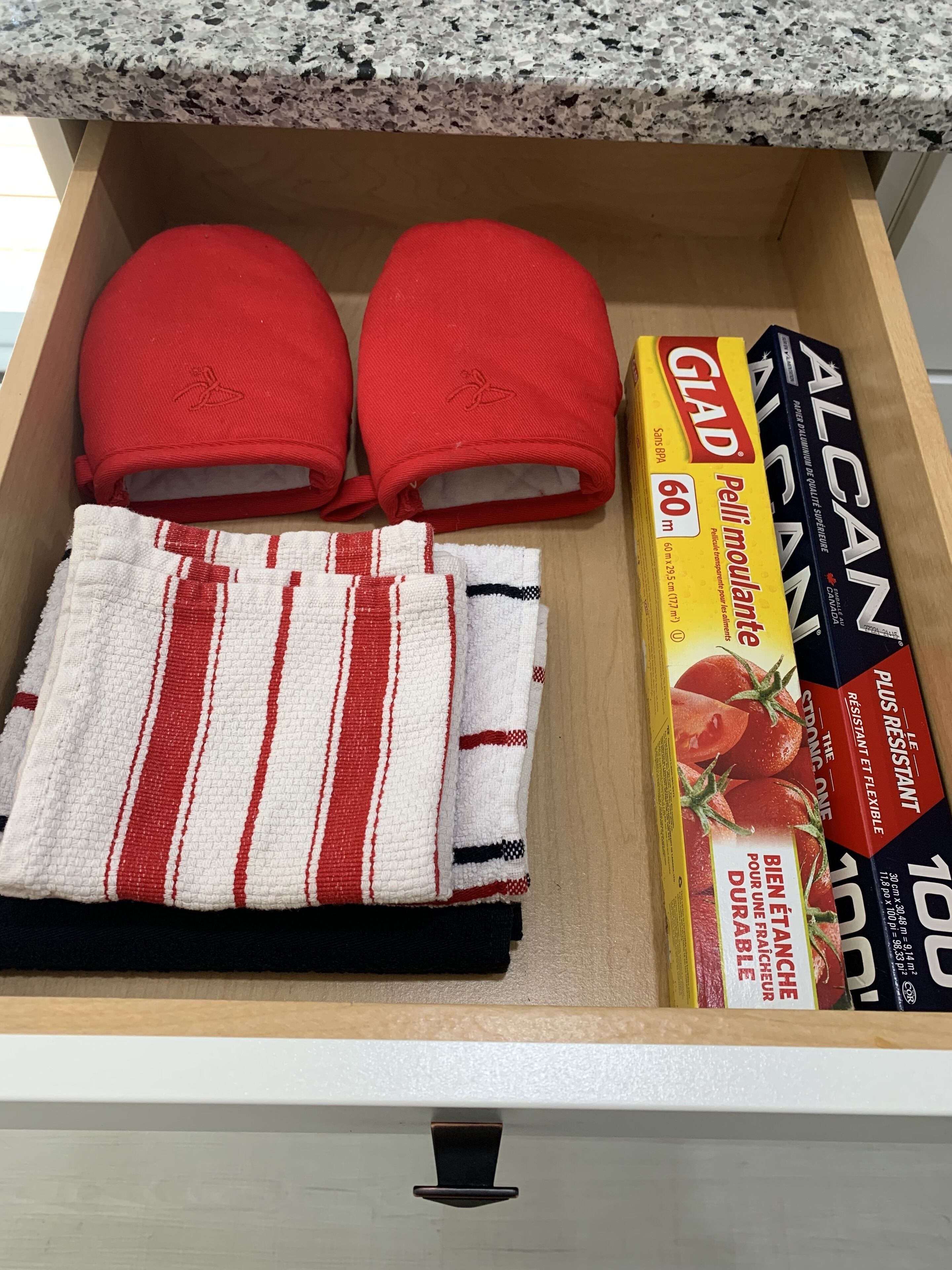 A drawer containing a red cap, a striped towel, and several boxes of pasta.
