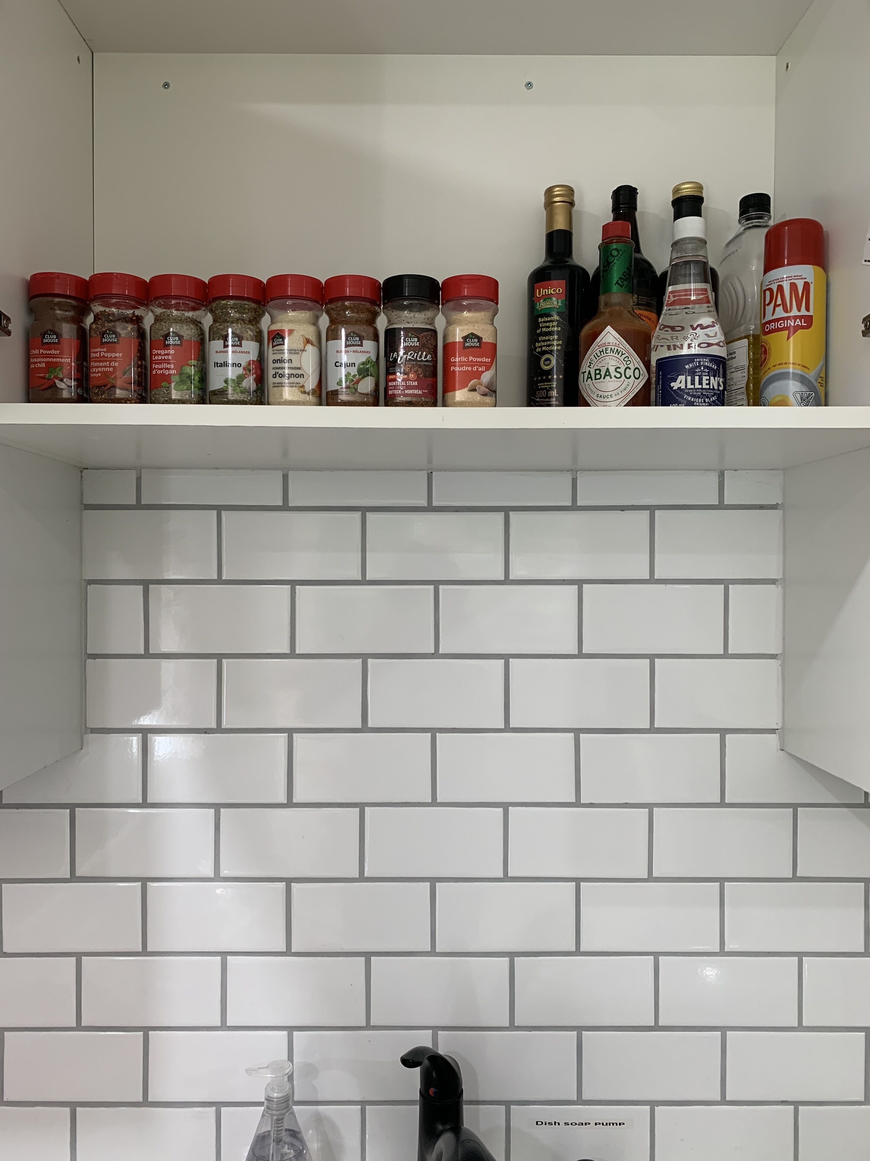 A kitchen with white subway tiles and a dish soap pump.