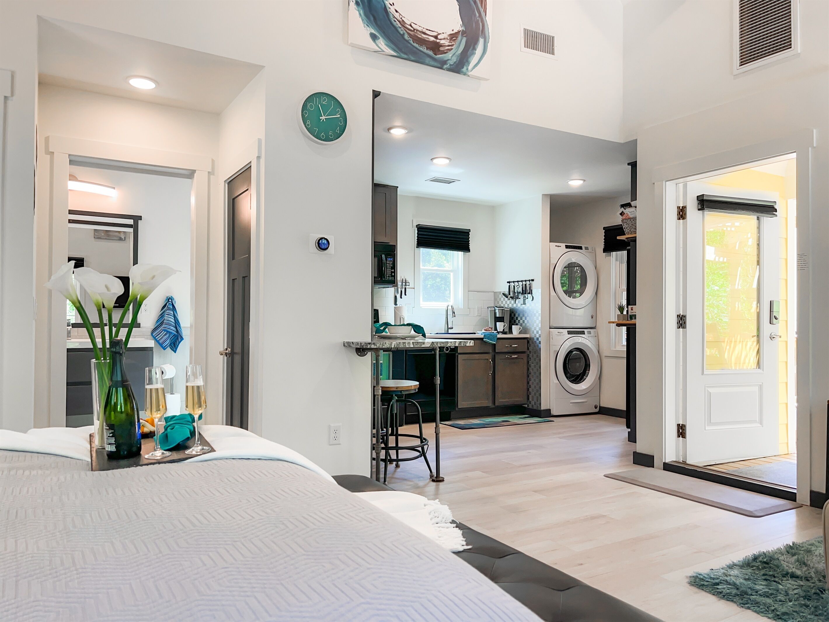 Una habitación de hotel moderna con una cama grande, un comedor, una cocina y zona de lavandería.