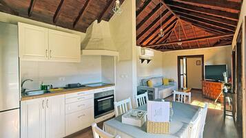 Une cuisine moderne avec des meubles blancs, un four encastré et un coin repas comprenant une table et des chaises.