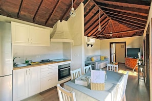 A modern kitchen with white cabinets, a built-in oven, and a dining area with a table and chairs.