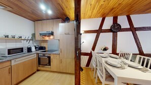 Een keuken met houten kastjes, een magnetron, een fornuis en een eethoek met een tafel gedekt voor twee personen.