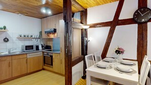 Een moderne keuken met houten kastjes, een magnetron en een eethoek met een tafel voor twee personen.