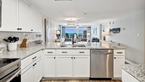 A modern kitchen with white cabinetry, a granite countertop, stainless steel appliances, and a view to the outdoors. - π 3BR/3BA π Ground Floor @ Pinnacle Port βοΈ π 50 π©΄π©΄ to the sand (Panama City Beach)