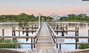 Une jetée en bois menant à une maison, sur laquelle est affiché un panneau d’avertissement concernant les exigences en matière de permis de pêche en Floride.