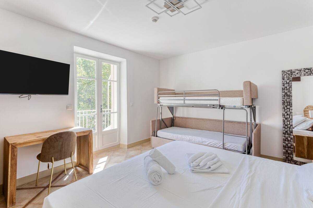 Een hotelkamer met een bed, bureau, stoel, televisie en raam.