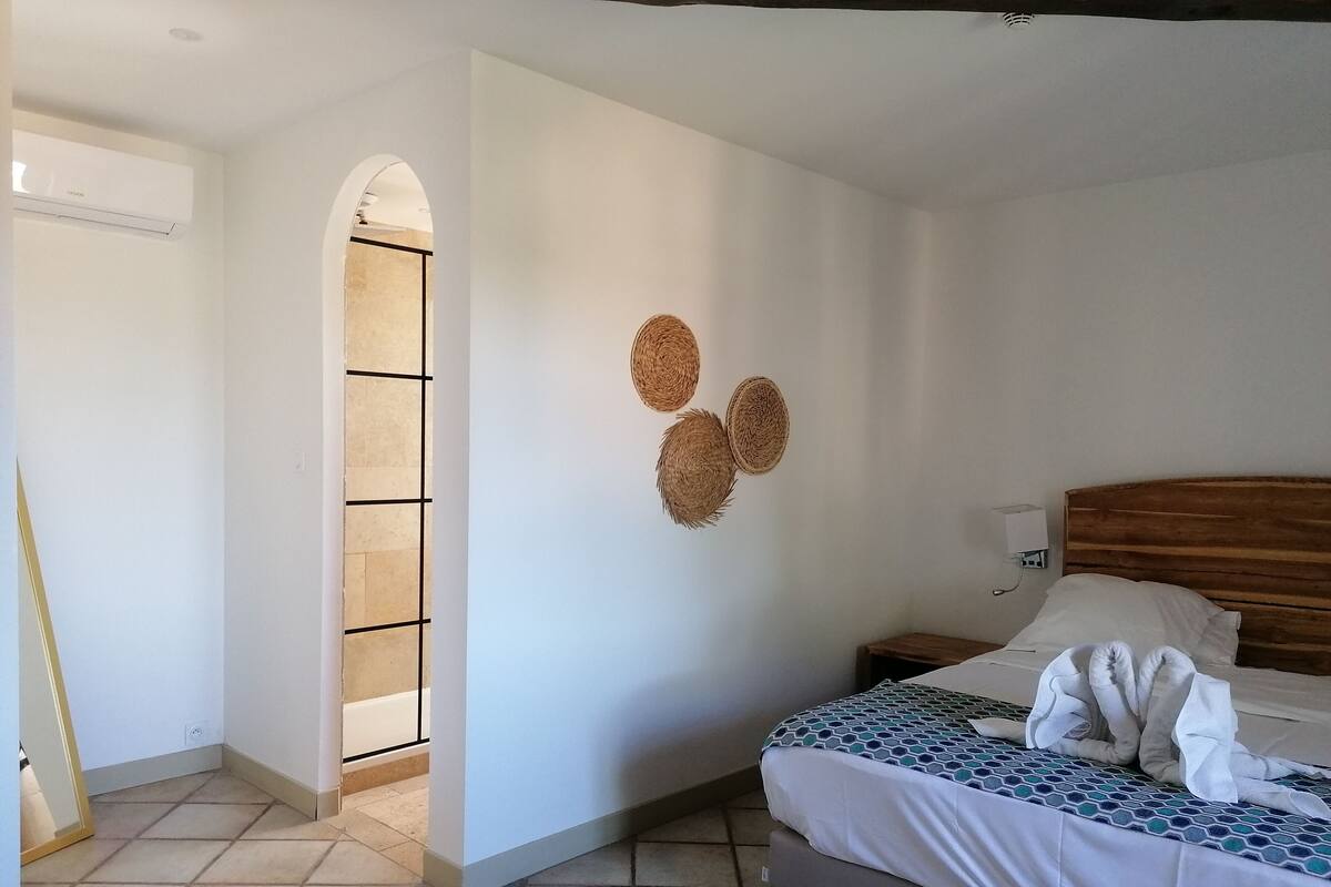 Een slaapkamer met een bed, een nachtkastje, een wandairconditioner en een betegelde vloer.