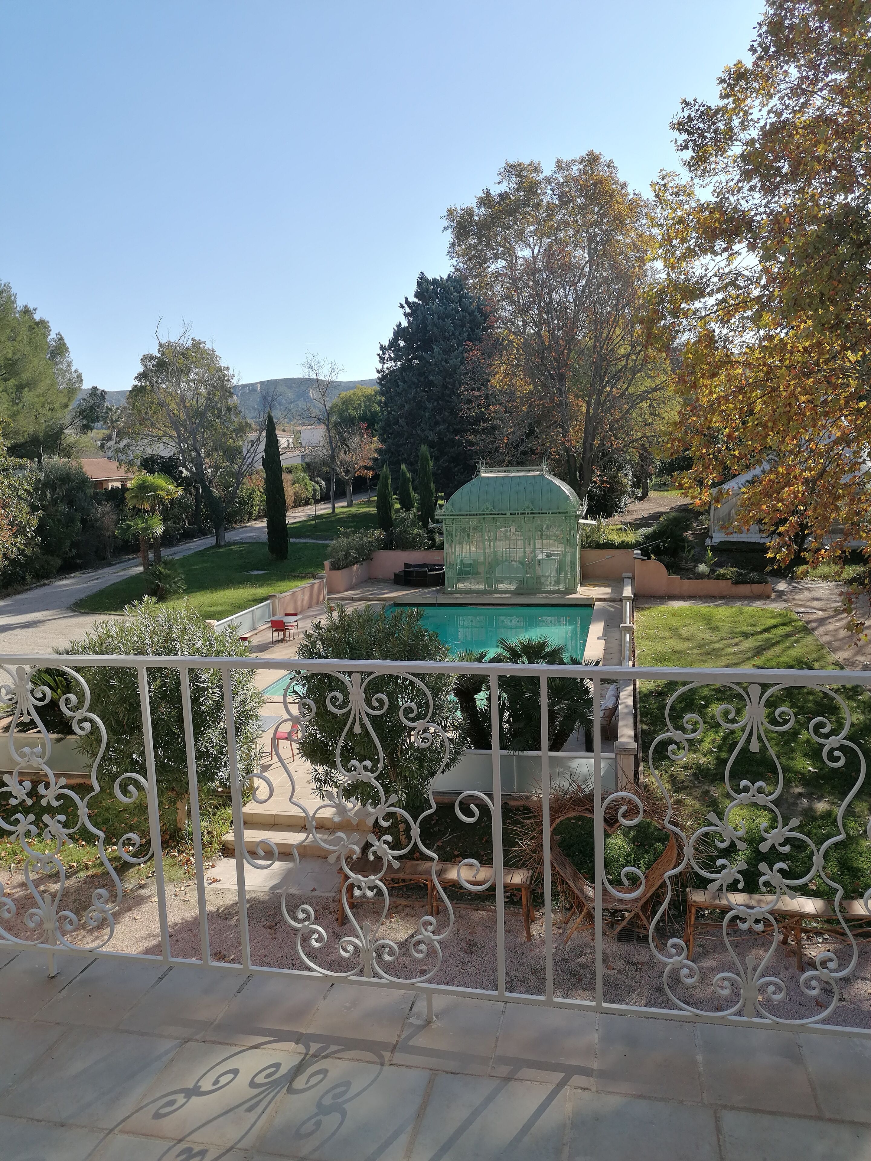 A garden with a swimming pool, a greenhouse, and a decorative fence.
