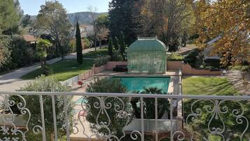 A garden with a swimming pool, a greenhouse, and a decorative fence.