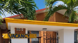 A property with a yellow and white exterior, a metal gate, and a sign indicating a vacancy. - Casa Terracota Bacalar (Bacalar)