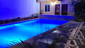 A swimming pool with blue lighting, a modern house with a door and windows, and a few potted plants. - Casa Terracota Bacalar (Bacalar)