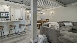 Ett modernt kök med en central köksö, barstolar och en matplats med bord och stolar.