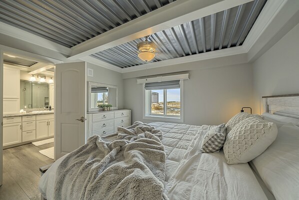 A bedroom with a bed, a window, a ceiling fan, and a view of the outdoors.