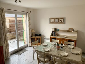 A dining area with a table set for four, a radio, and a bookshelf with books and decorative items.