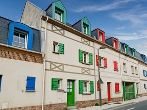 A row of buildings with distinctively colored roofs and shutters, a street lamp, and a clear sky.