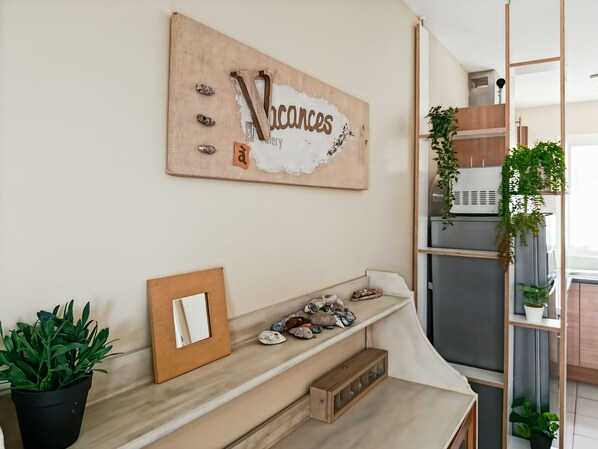 A kitchen with a wooden countertop, a hanging plant, and a wall-mounted artwork.