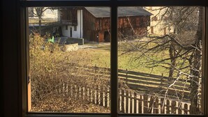 A window view of a building with a wooden fence, a clear sky, and a mountain in the background. - Traditional vacation apartment in rustic style with view of the Schlern (Völs am Schlern)