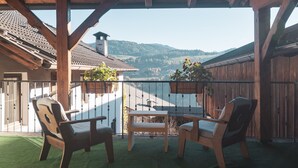 A covered patio with wooden chairs and a table, overlooking a mountainous landscape. - Traditional vacation apartment in rustic style with view of the Schlern (Völs am Schlern)