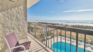 Een balkon met uitzicht op het strand en een zwembad.