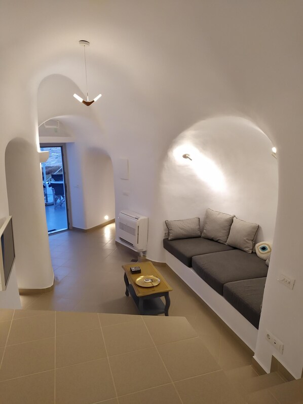 Un salon moderne avec un canapé, une petite table et un luminaire au plafond.