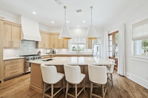 A modern kitchen with wooden cabinets, a central island with bar stools, and pendant lighting.