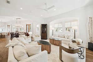A spacious living room with a large sofa, coffee table, and dining area with chairs.