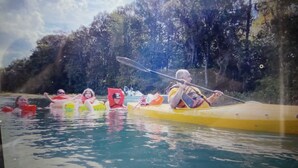 A group of people kayaking on a river surrounded by trees.