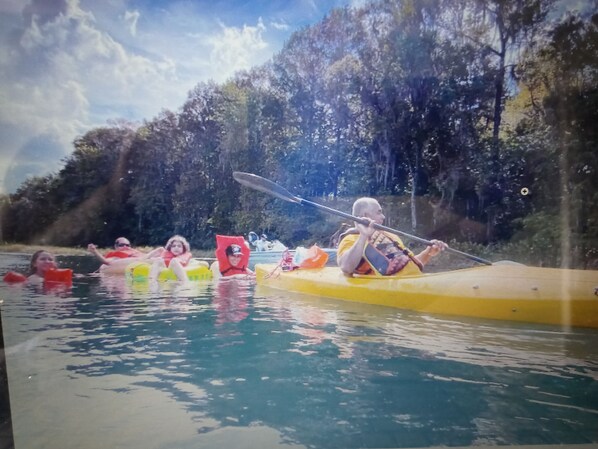 A group of people kayaking on a river surrounded by trees.
