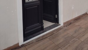 Una porta negra amb marc blanc i una petita finestra a dalt.