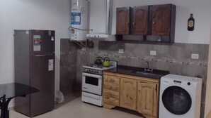 Una cuina compacta amb nevera, fogó, forn i rentadora.