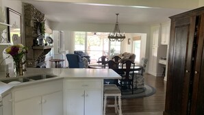 A spacious kitchen with a large island, white cabinetry, and a dining area with blue chairs. - Bluebird Rest - Peaceful Lake Retreat (Kelso)