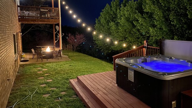 A backyard with a hot tub, string lights, a deck, and a covered patio area. - 4BR Duplex w/ Hot Tub & Fire Pit | Pet Friendly | Group Stay | DV 166 (Branson)