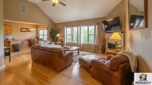 A spacious living room with a large brown leather sofa, a television, and a fireplace. - 4BR Duplex w/ Hot Tub & Fire Pit | Pet Friendly | Group Stay | DV 166 (Branson)