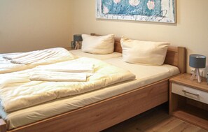 A neatly made bed with white linens, a wooden headboard, and a bedside table with a lamp.