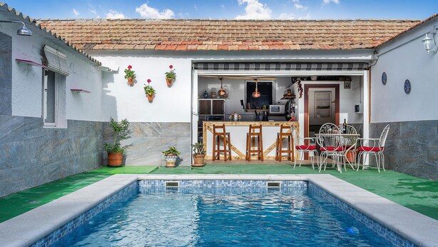 Zona junto a la piscina con bar y asientos.