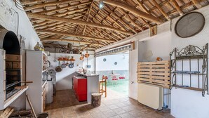 Una cocina rústica con techo de madera, un refrigerador rojo y una zona de comedor con mesa y sillas de madera.
