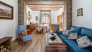 Una sala de estar acogedora con un sofá azul, sillas de madera, una mesa de centro y una pared de piedra.