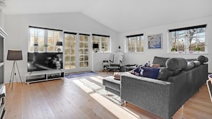 A spacious living room with a grey sofa, a flat-screen TV, and a large window with multiple panes. - 3 bedroom amazing home in Glesborg (Glesborg)